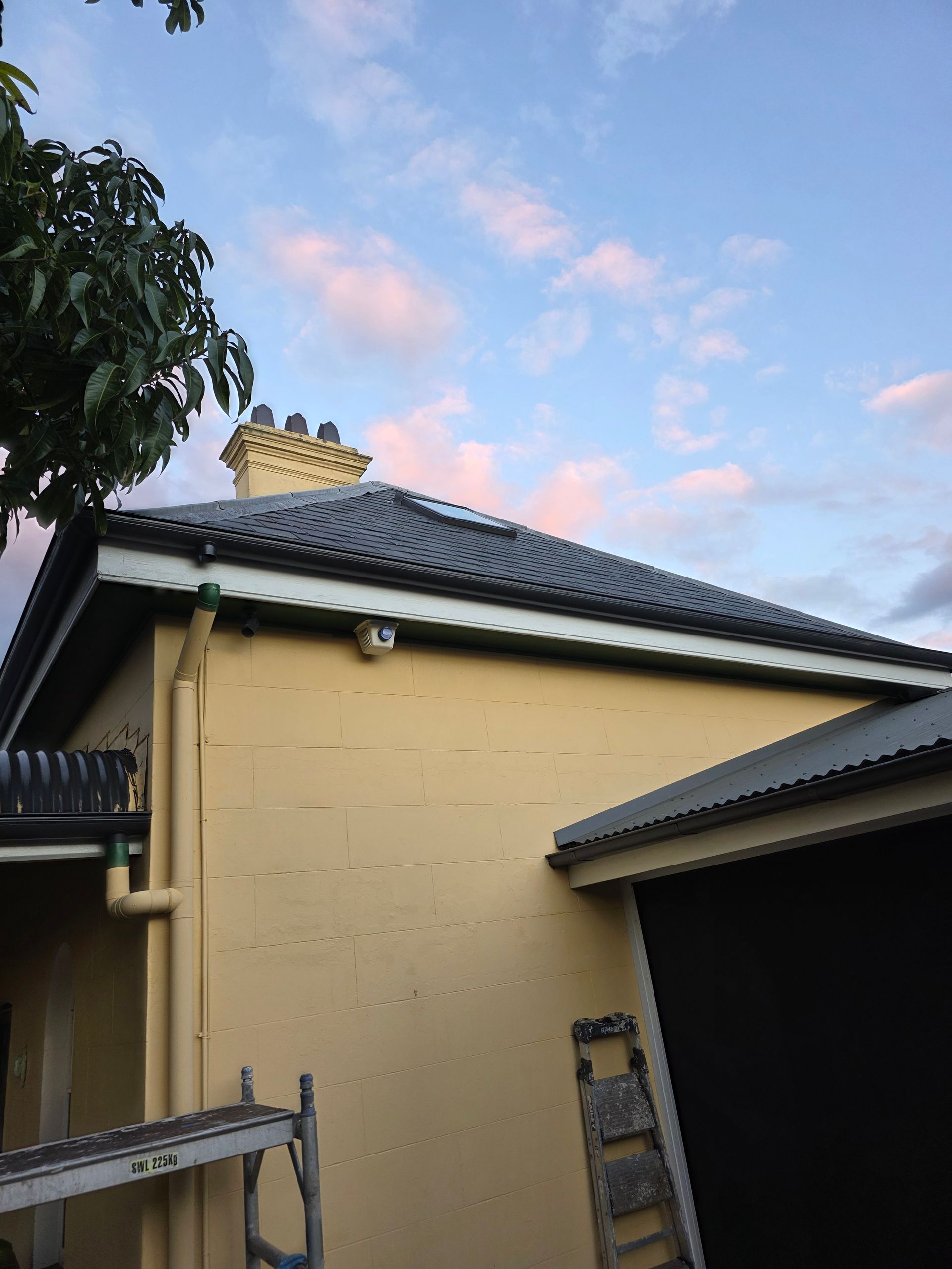 A House With a Black Roof, Chimney, and Gutters — McLuckie Metal Roofing In Bankstown, NSW