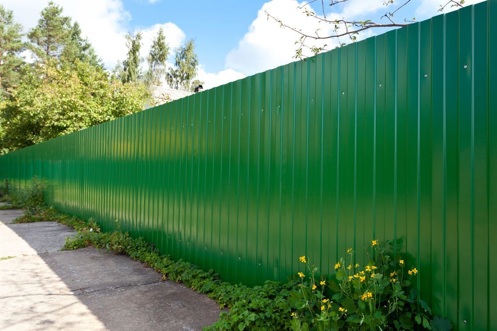 Green Corrugated Metal Fence Along a Sidewalk — McLuckie Metal Roofing In Liverpool, NSW
