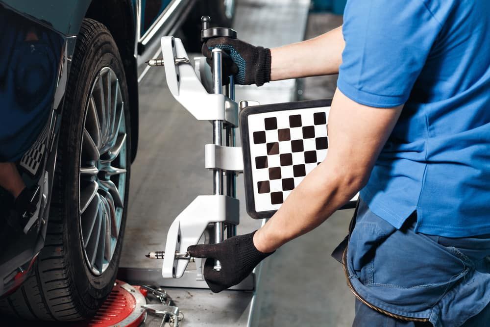 A Man Is Adjusting A Tyre On A Car With A Machine — Tyrepower Innisfail In Mission Beach, QLD