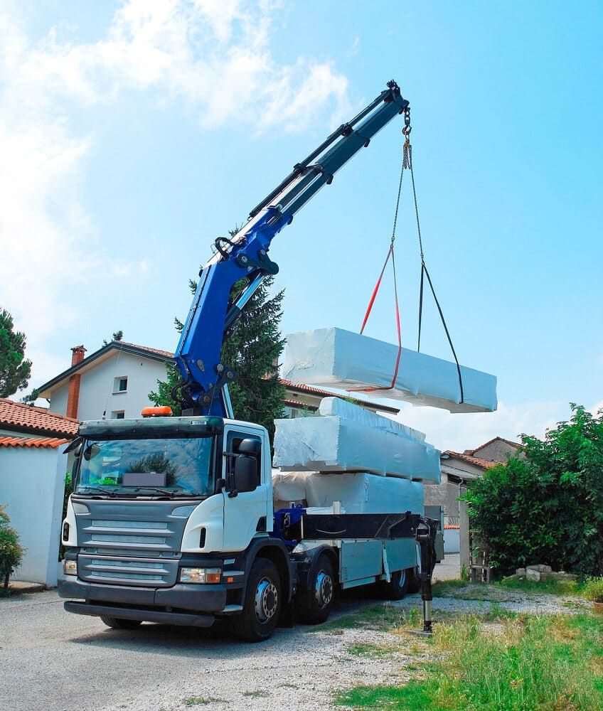 A Truck With A Crane Attached To It Is Lifting A Stack Of Blocks — Tyrepower Innisfail In Babinda, QLD