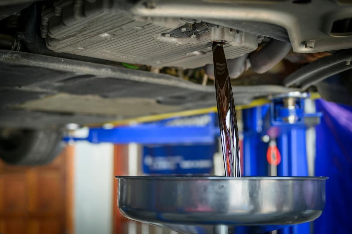 The Oil Is Being Poured Into A Bucket Under The Car — Tyrepower Innisfail In Mission Beach, QLD