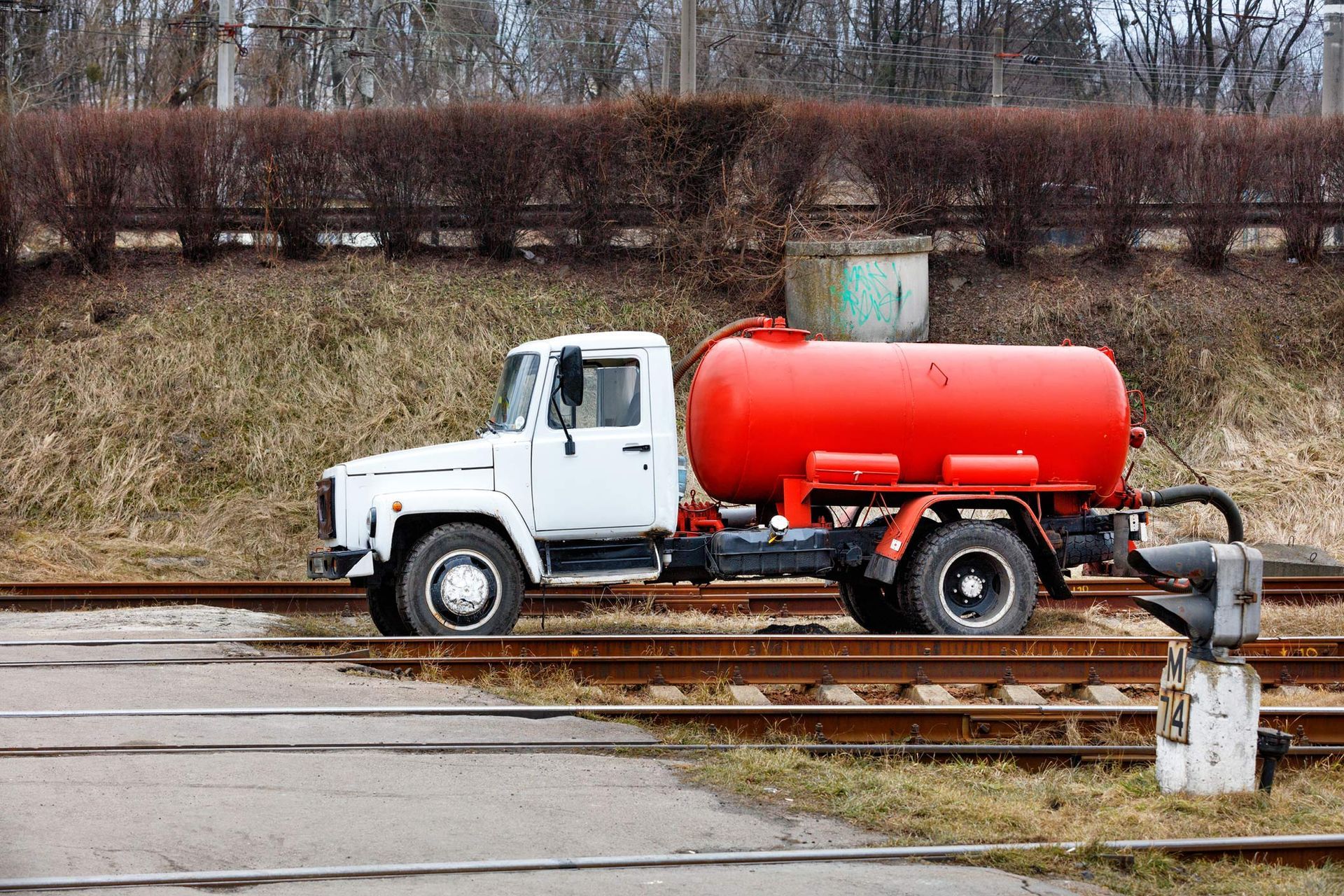 Sewage truck on pumping feces with a bright red cistern.