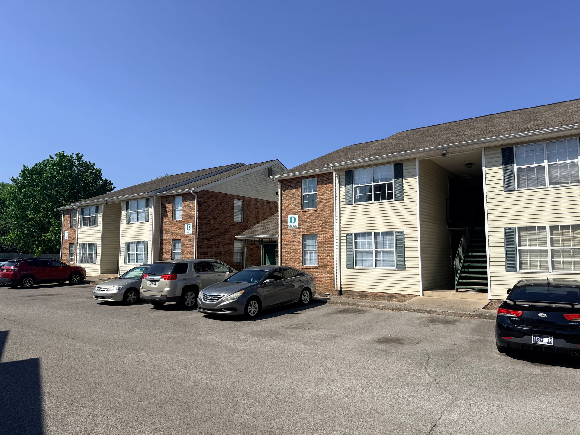 Apartment complex parking lot with parked cars under a clear blue sky