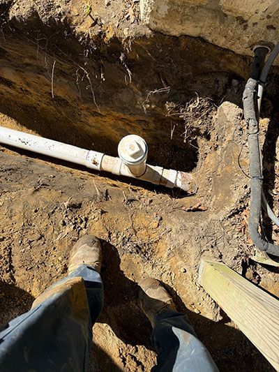 Exposed underground pipes in a dirt trench during plumbing repair