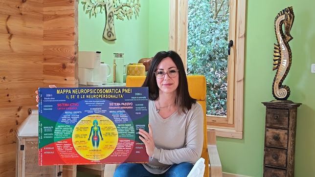 Una donna tiene in mano un colorato poster educativo in una stanza di legno con una grande finestra e decorazioni alle pareti.