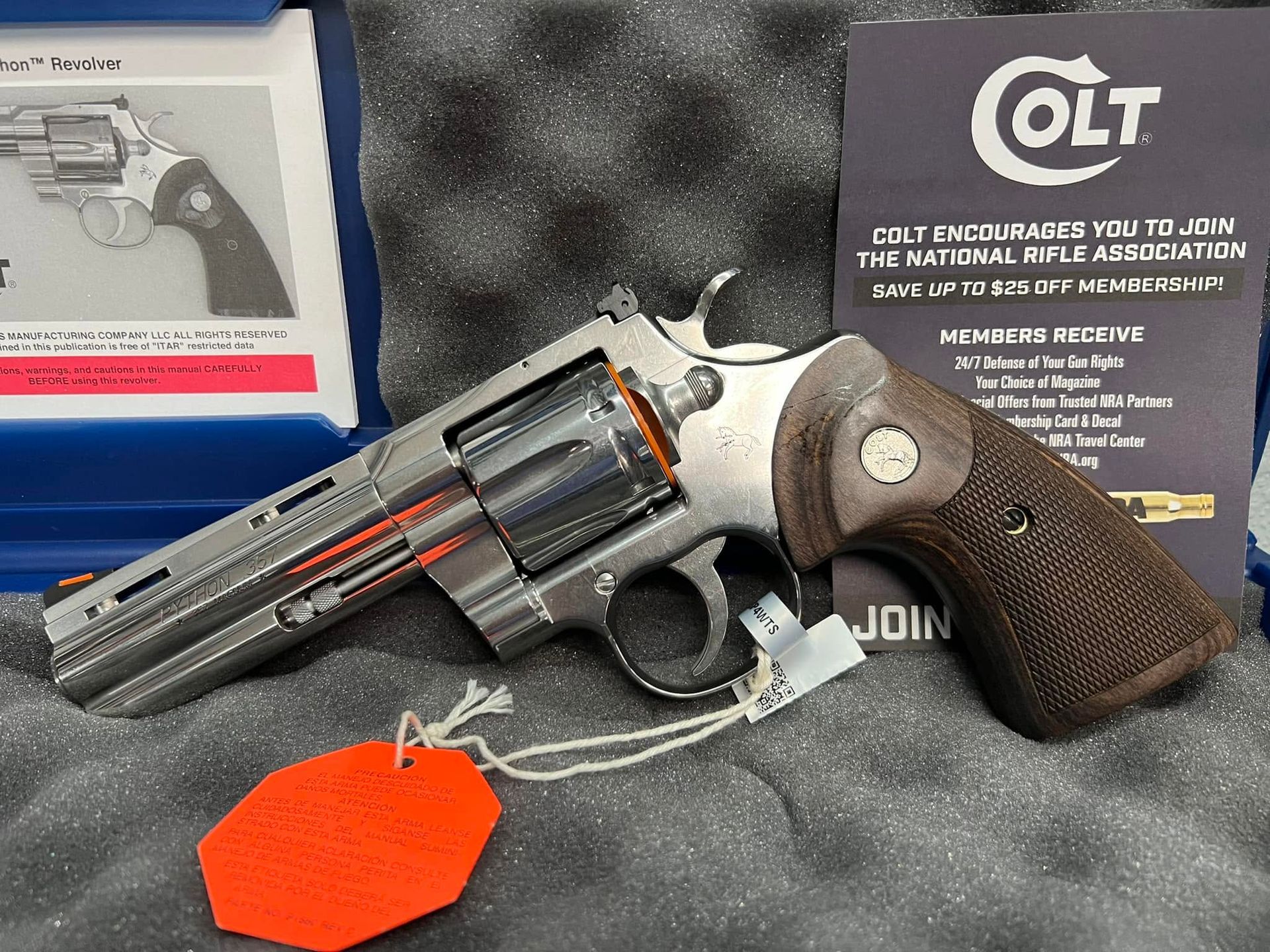 Silver Colt revolver with brown grip, orange tag, and box in a foam-lined case