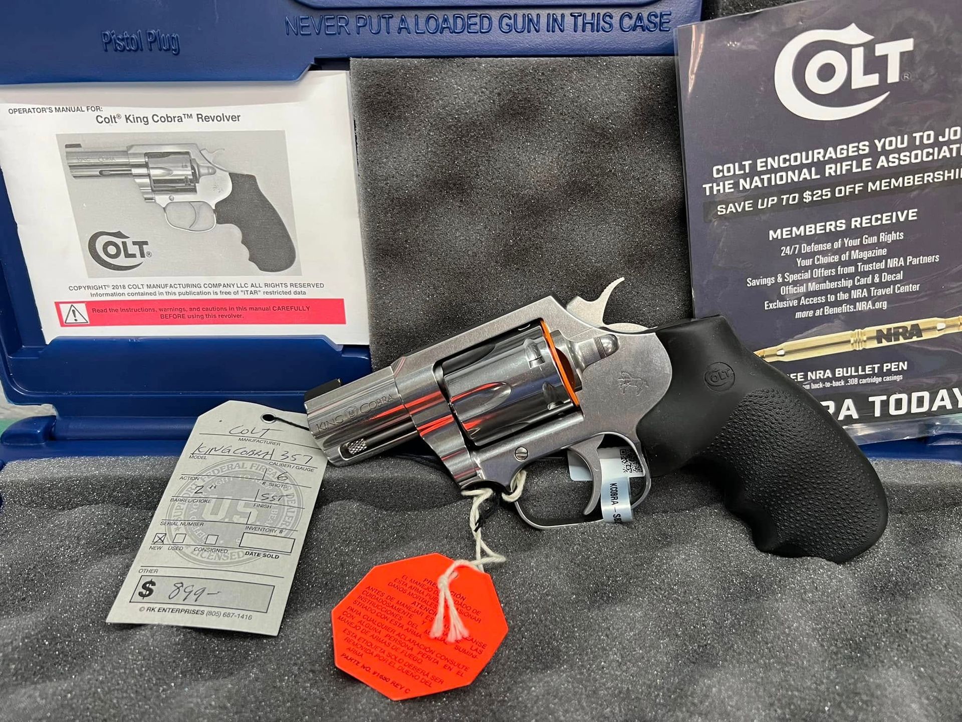 Revolver with box, instruction sheet, and orange tag displayed on gray fabric background