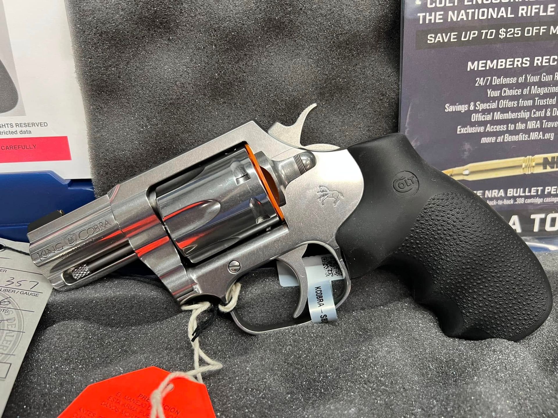 Black and silver revolver with orange safety tape on a foam display stand.