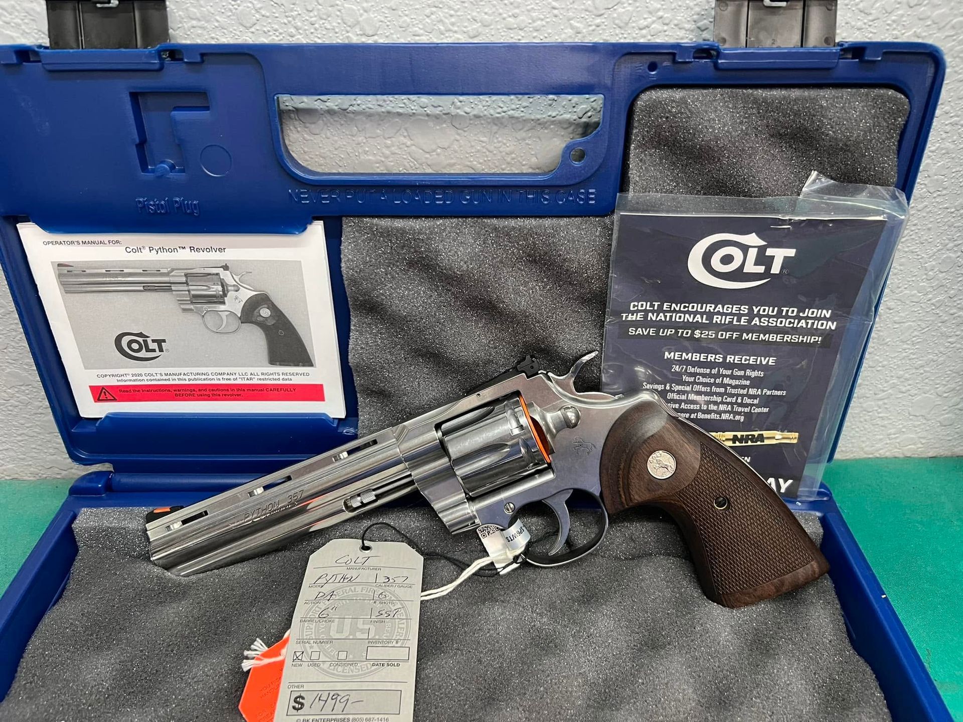Revolver in blue case with QLT manuals and accessories, on a teal tabletop.