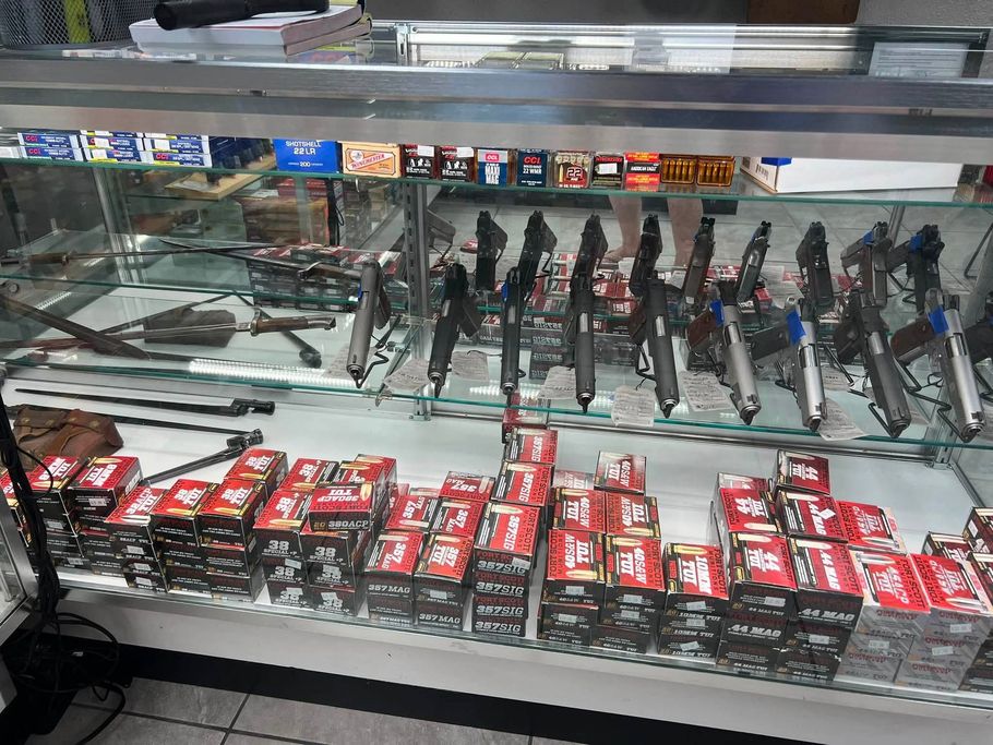 Glass display case with rows of black items and red-packaged goods on shelves in a store.