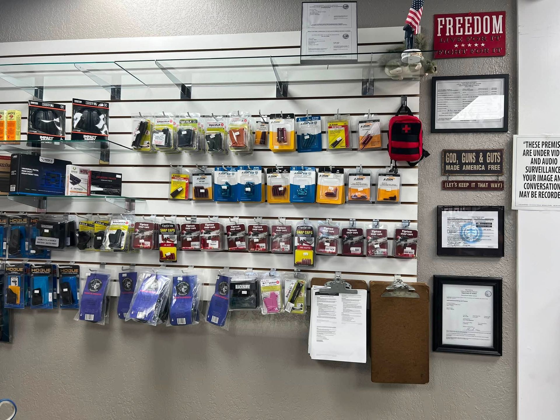 Wall of assorted packaged accessories on display slatwall, with framed certificates on the right