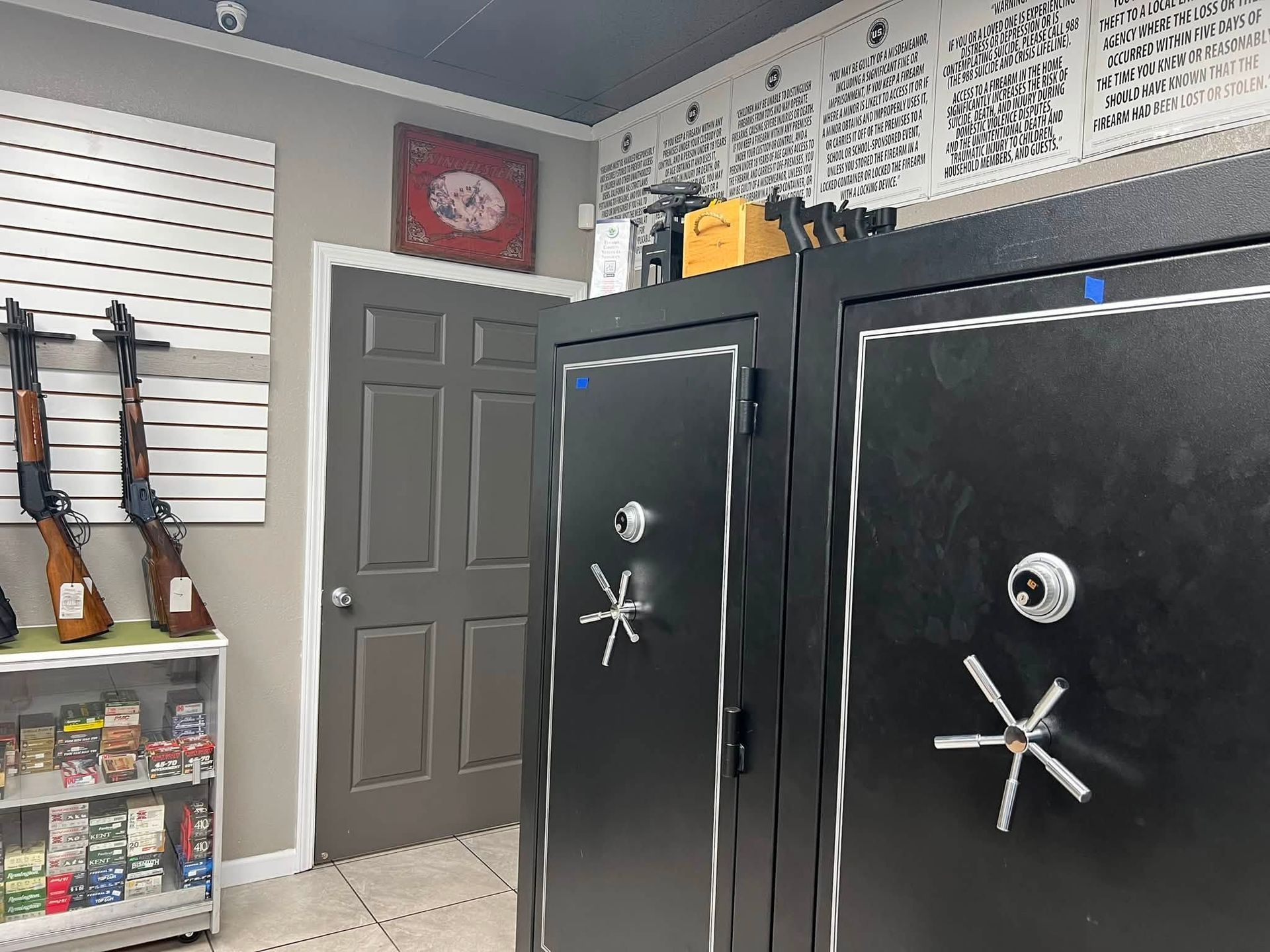 Two black safes in a garage or workshop with shelves, tools, and a gray door in the background
