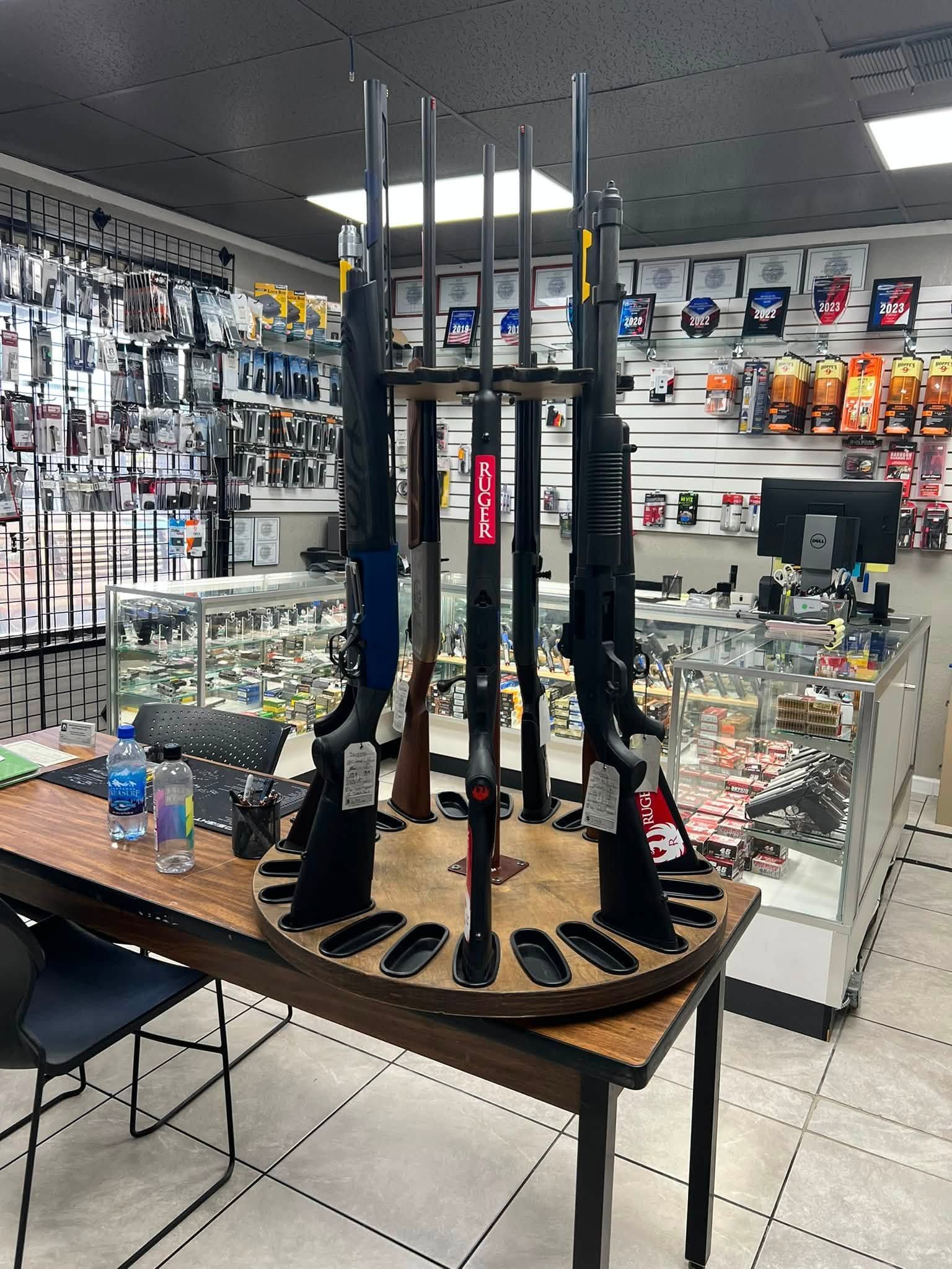Hunting gear display with rifles and accessories on a round table in a store.