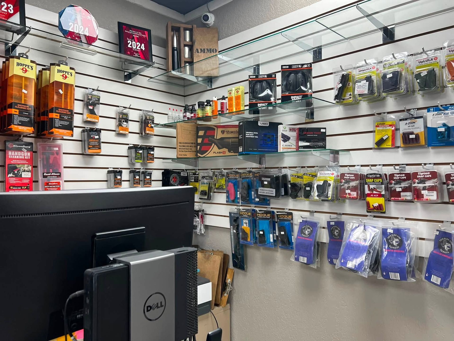 Electronics store aisle with phone accessories displayed on wall racks and a Dell computer monitor in front