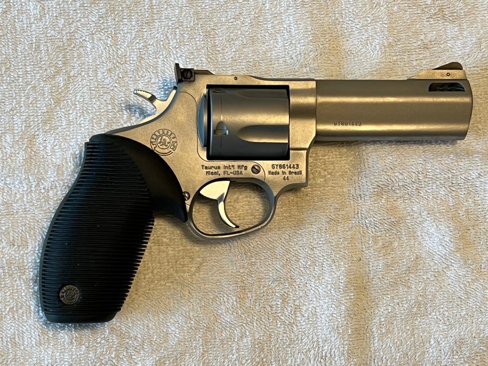 Small silver revolver with black grip lying on a light carpet.