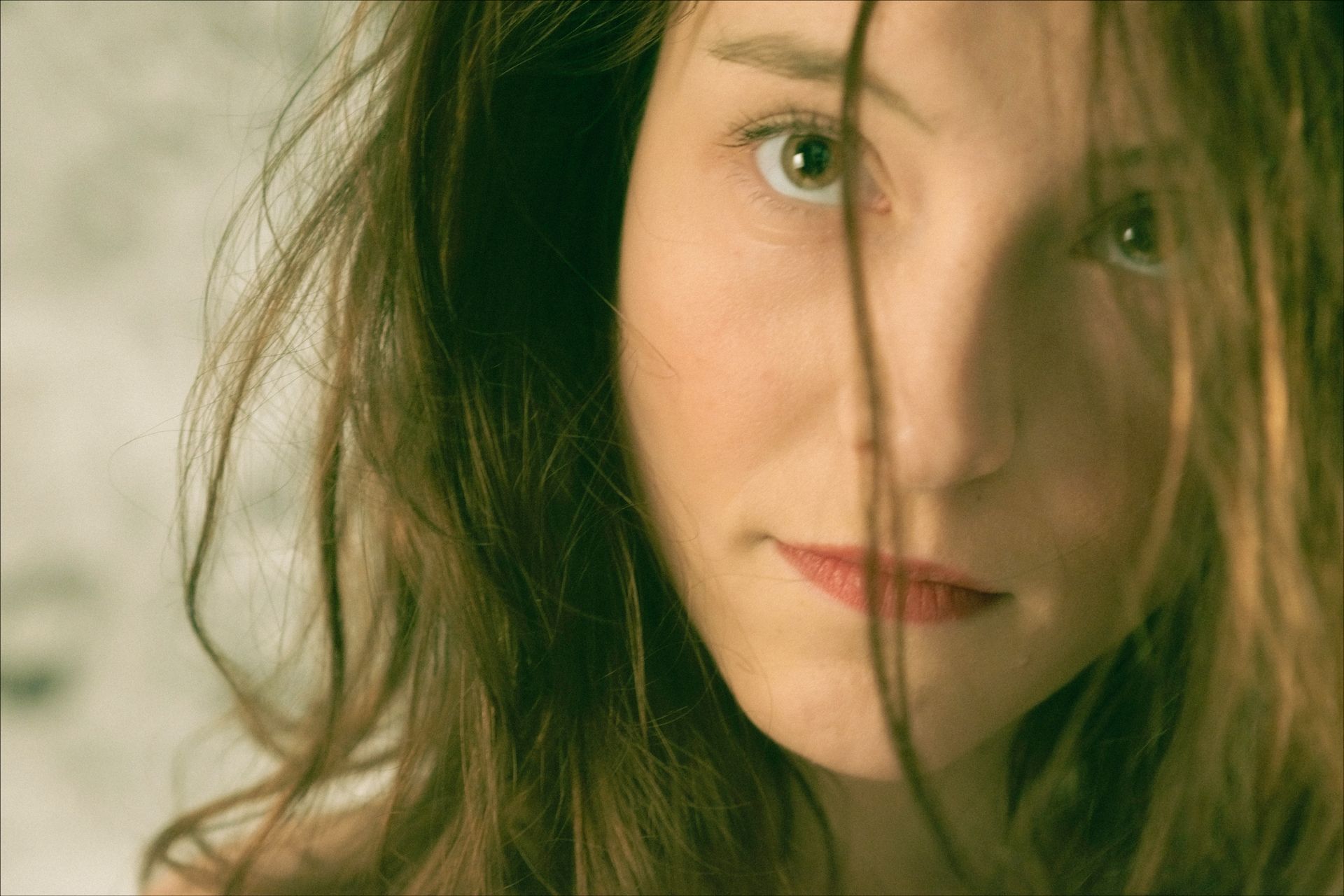 Woman with messy brown hair, looking directly at the viewer with a neutral expression.