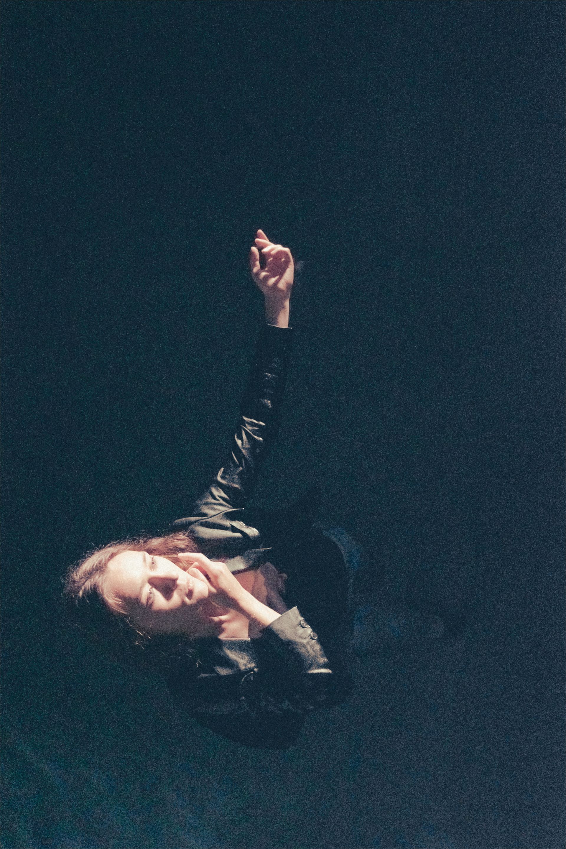 Person in dark water reaches upward, dark setting.