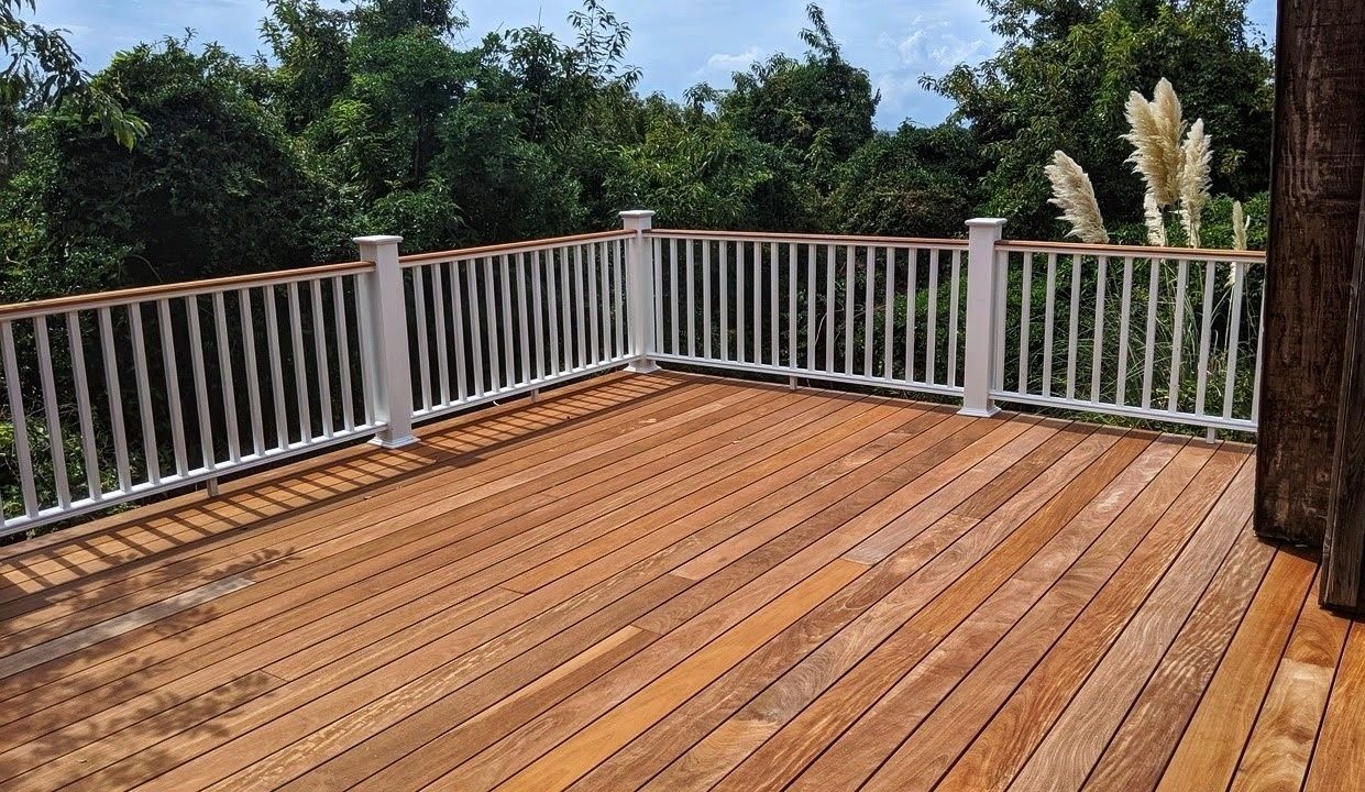 Wooden deck with white railing overlooking a lush green forest.