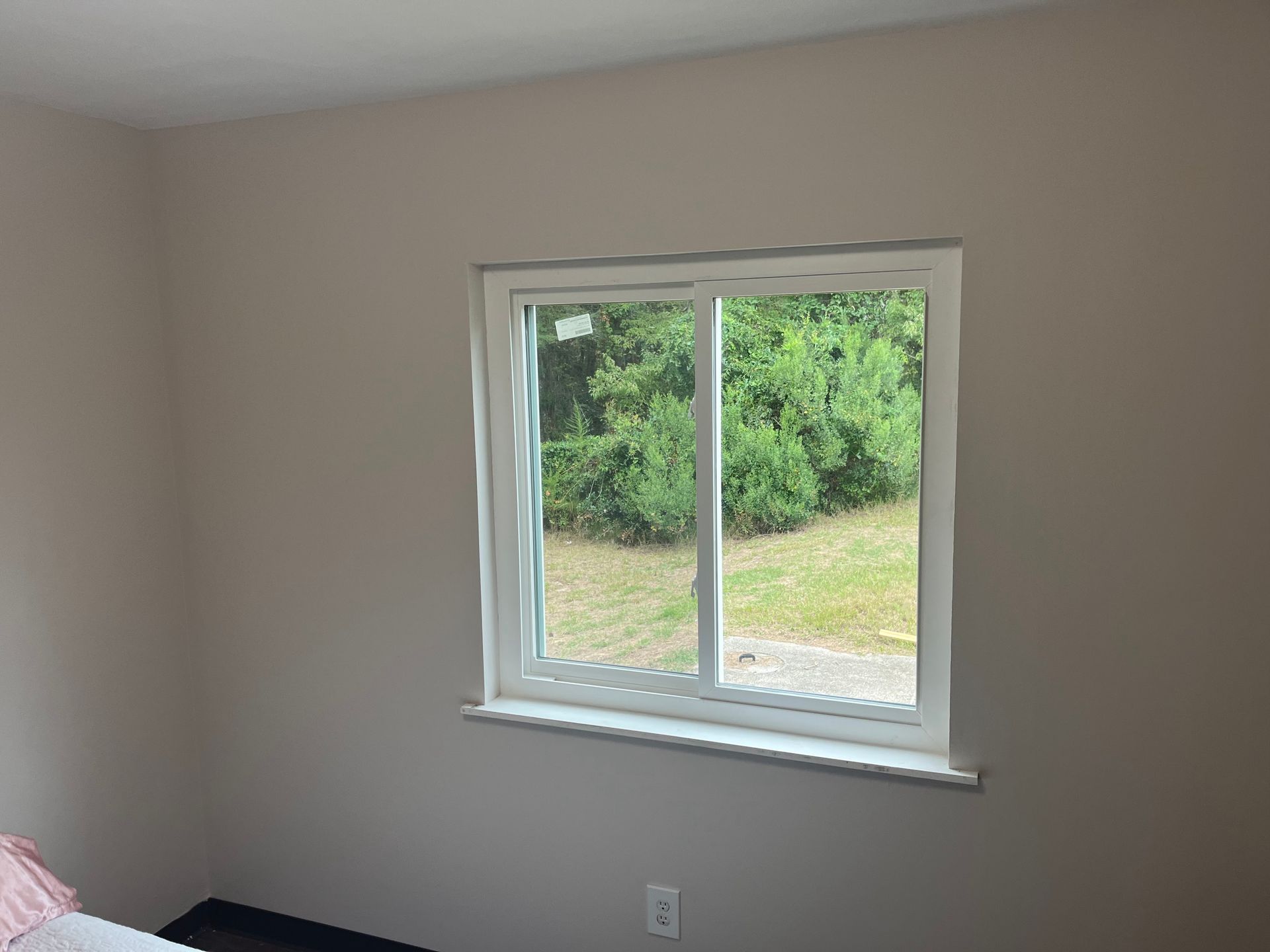 A window in a room with a view of green trees and grass.