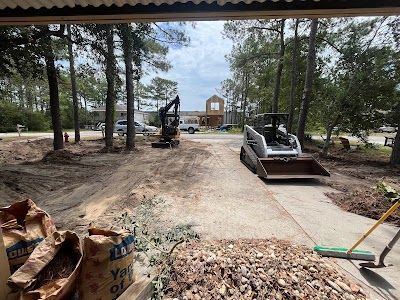Construction site with small excavator, skid steer, and landscaping debris.
