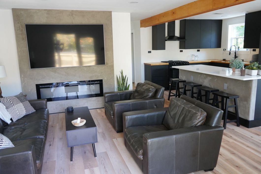 Modern living room with black leather seating, fireplace, and open kitchen with a breakfast bar.