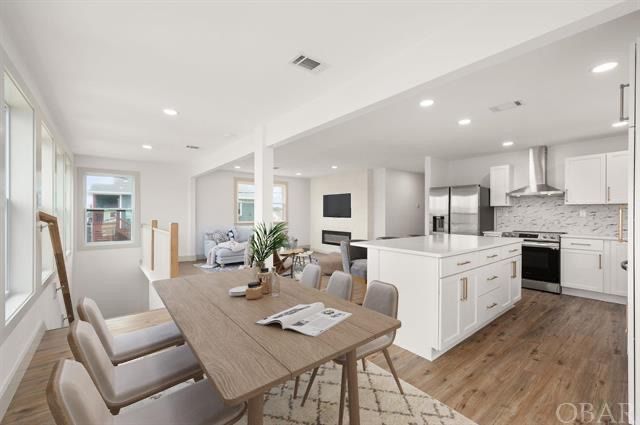 Open-concept kitchen and dining area with white cabinets, island, and light wooden floors.