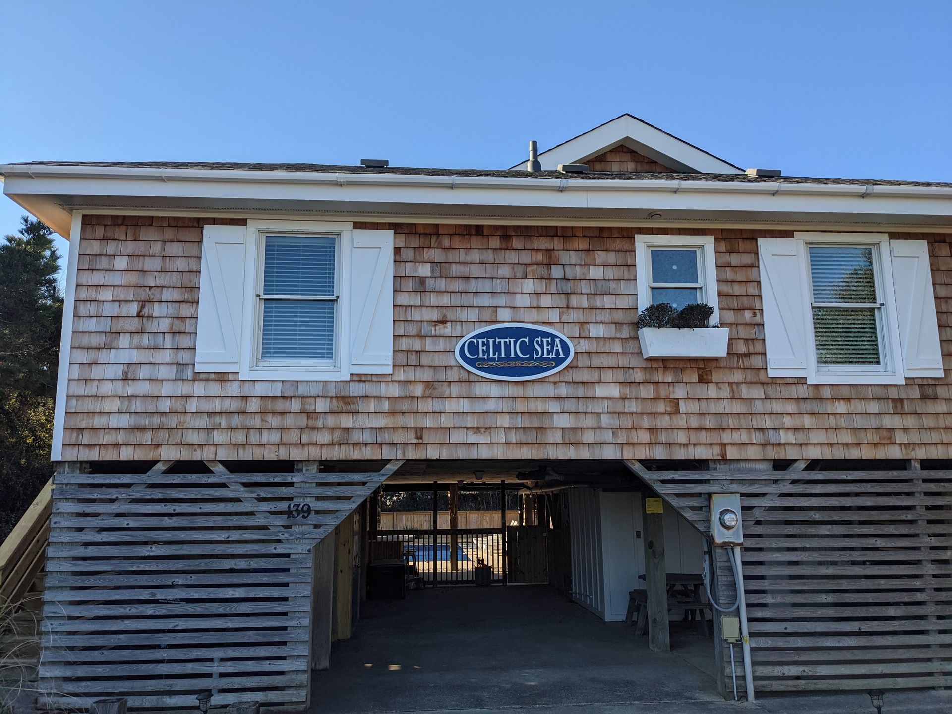 Wooden beach house on stilts with a sign that says 