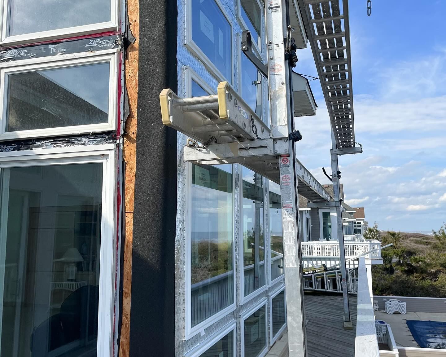 Scaffolding next to building with windows; exterior construction in progress on a sunny day.