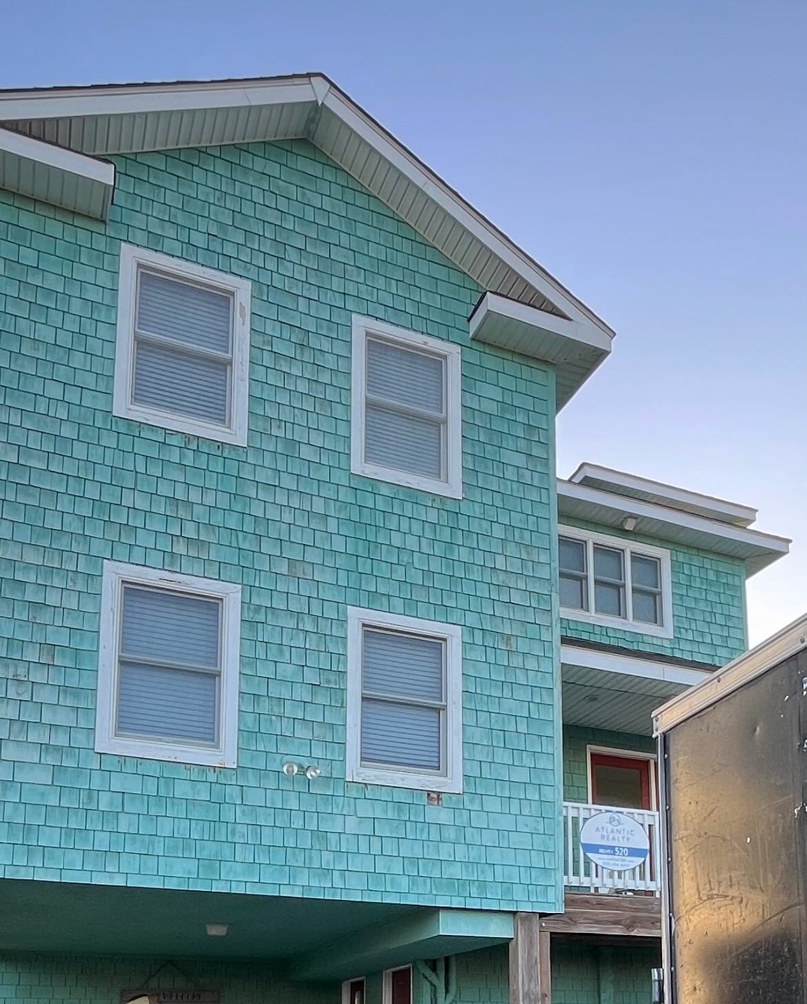 Two-story teal house with white trim and windows.