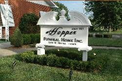 White Hope Funeral Home sign in front of a building, surrounded by grass and shrubs.