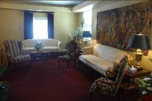 Cozy living room with cream sofas, red carpet, a window, lamps, and a large wall tapestry
