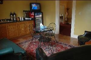 Small living room with red rug, glass table, wooden cabinets, and a TV against the wall.