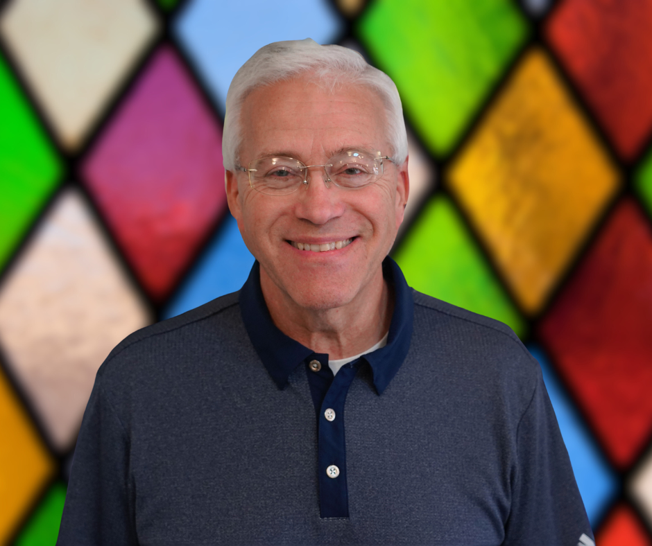 A man is smiling in front of a stained glass window