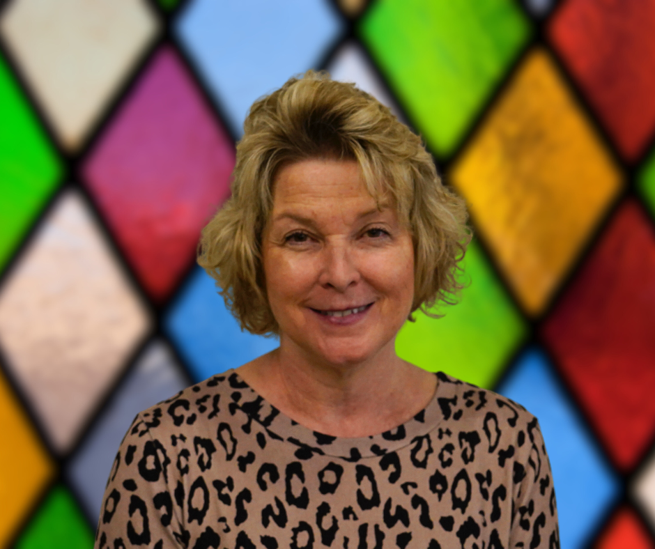 A woman in a leopard print shirt is smiling in front of a stained glass window