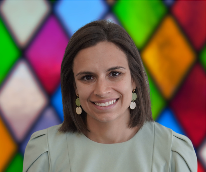 A woman is smiling in front of a stained glass window