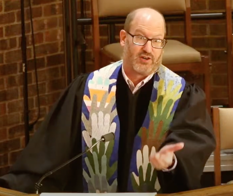 A man in a robe with hands on it is giving a speech