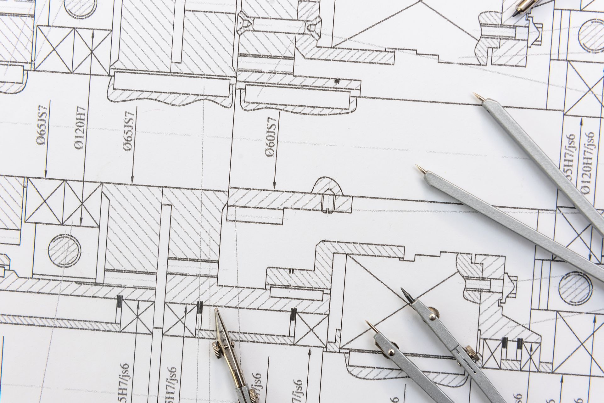 House drafting service plans with pencils and a compass on technical blueprint drawings.