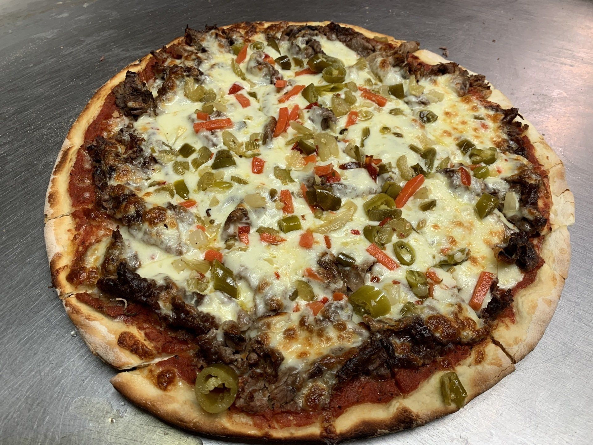 A pizza with a lot of toppings on it is sitting on a table.