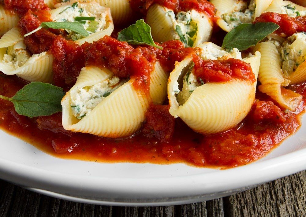 A white plate topped with stuffed shells and tomato sauce