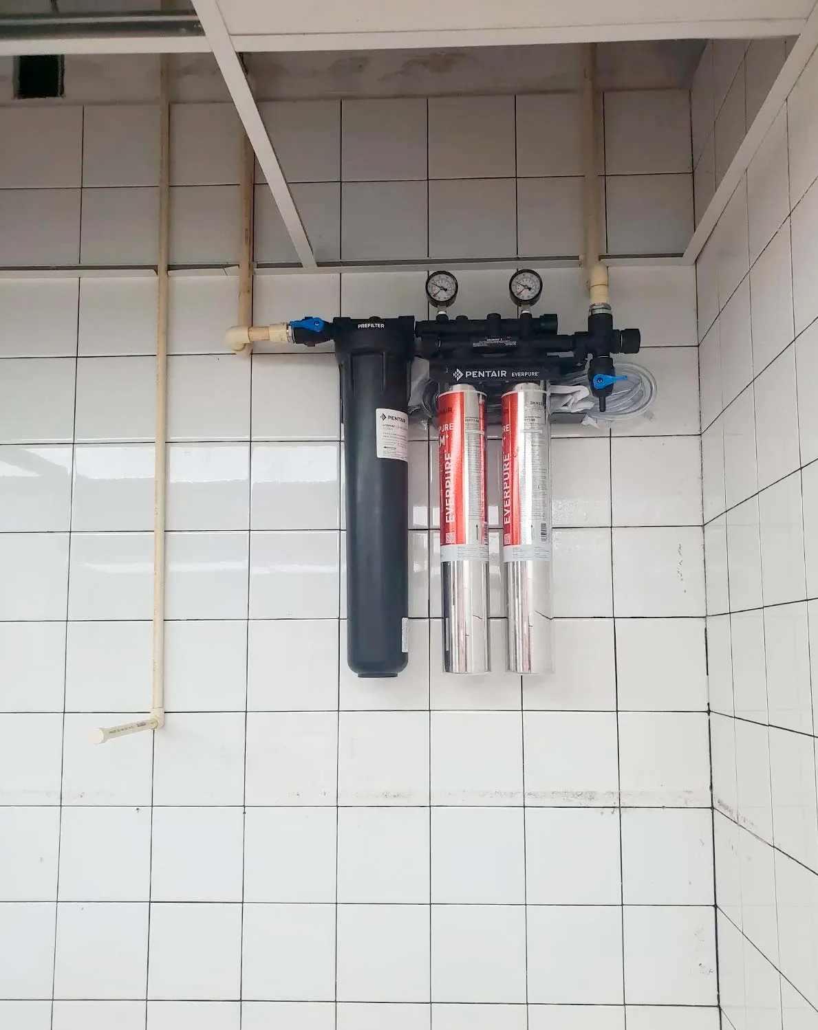 A water filter is hanging from the ceiling in a bathroom.