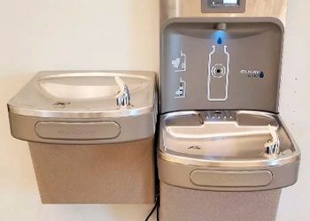 Two water fountains are sitting next to each other on a wall.