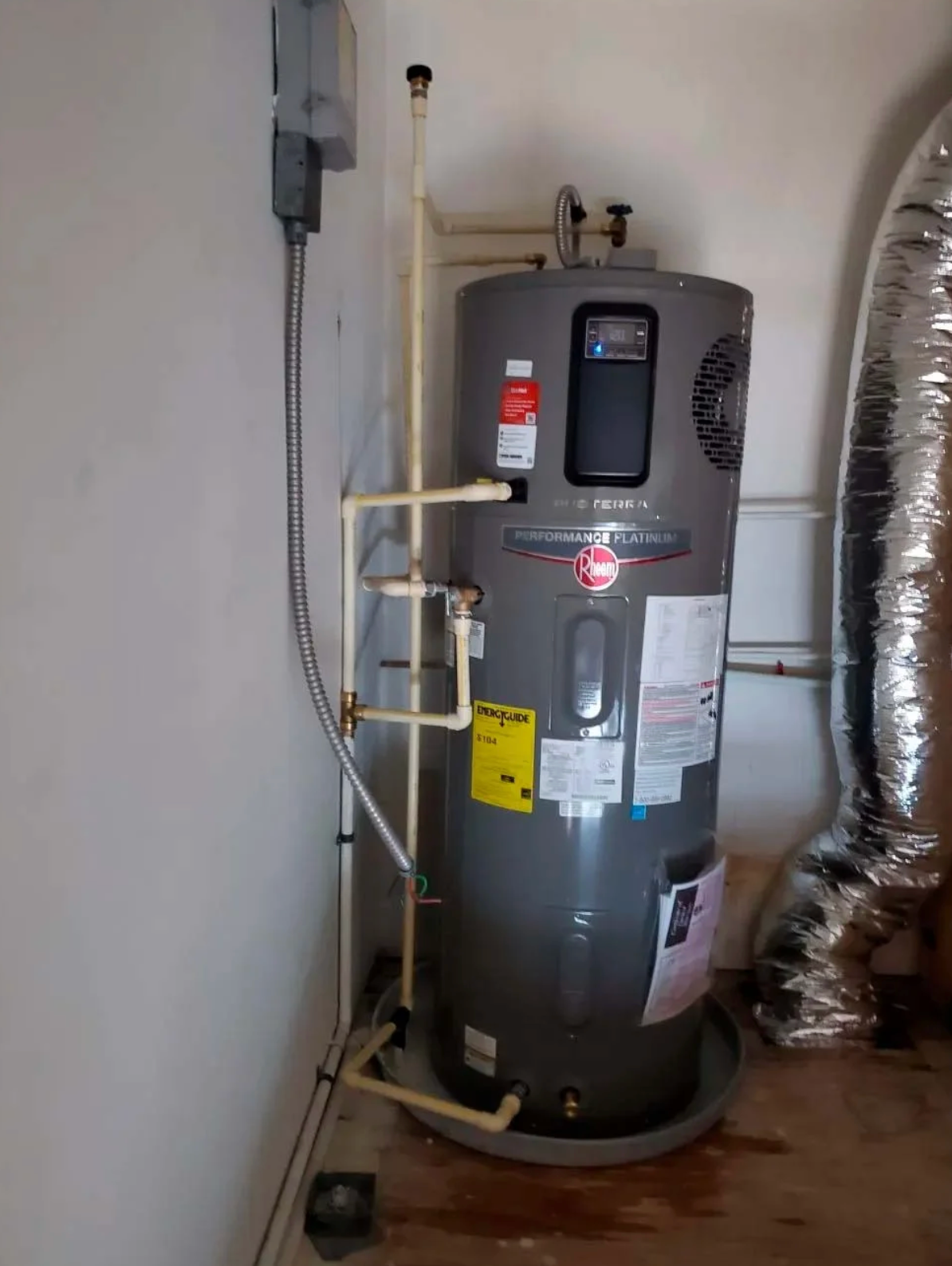A water heater is sitting in a room next to a wall.
