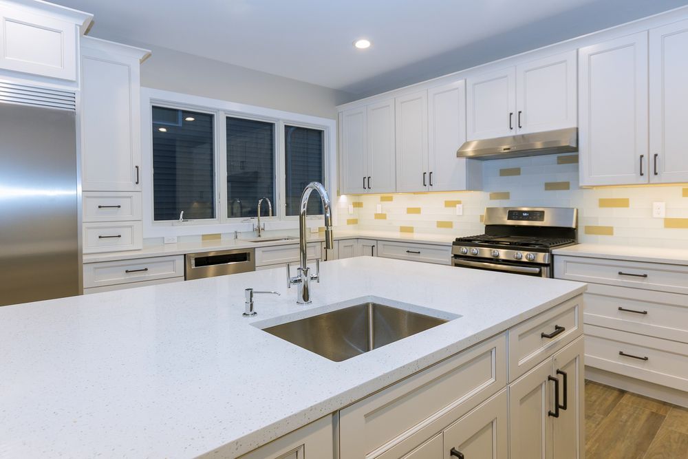 Bright white modern kitchen with island, stainless steel appliances, and large window over the sink
