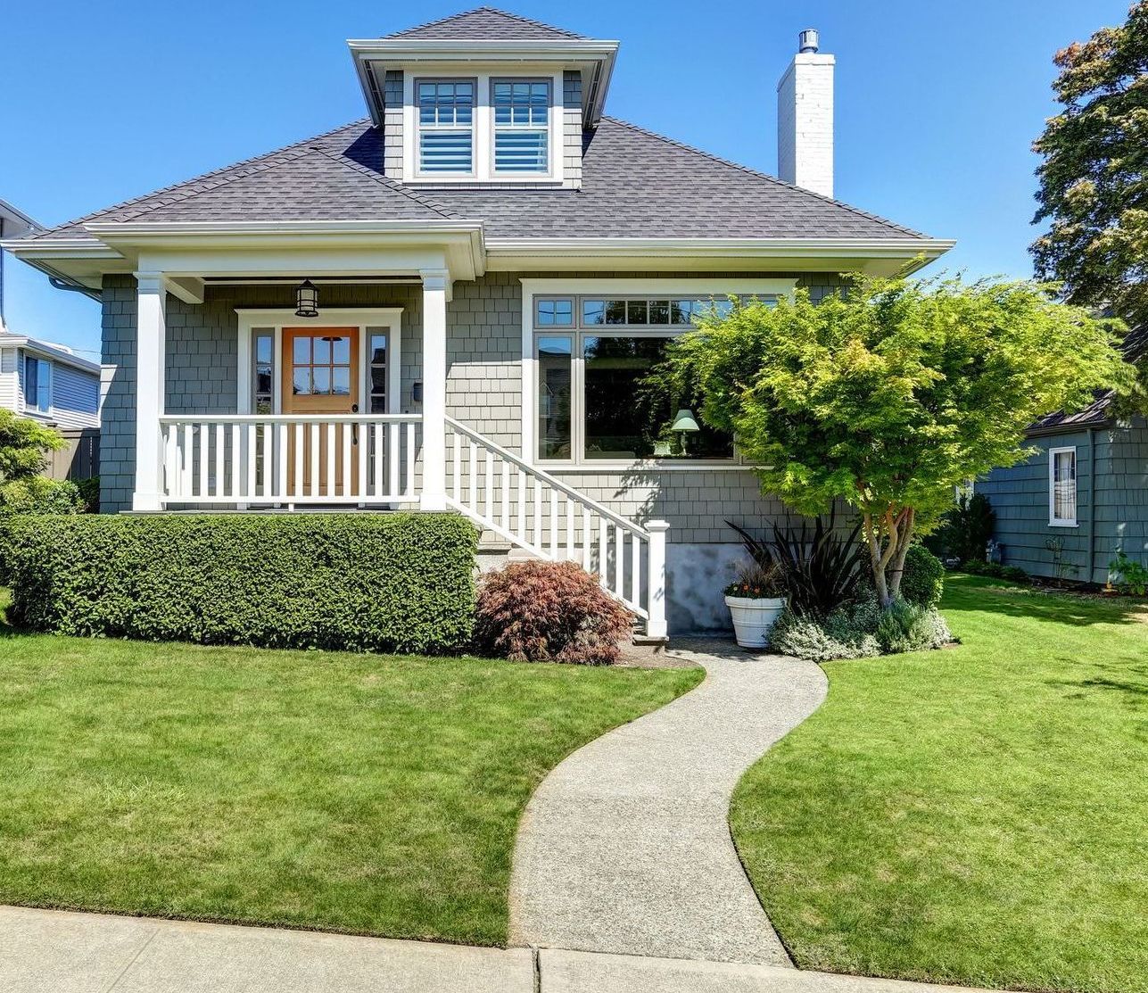 Charming Craftsman-style house with green siding, a walkway, and manicured lawn.