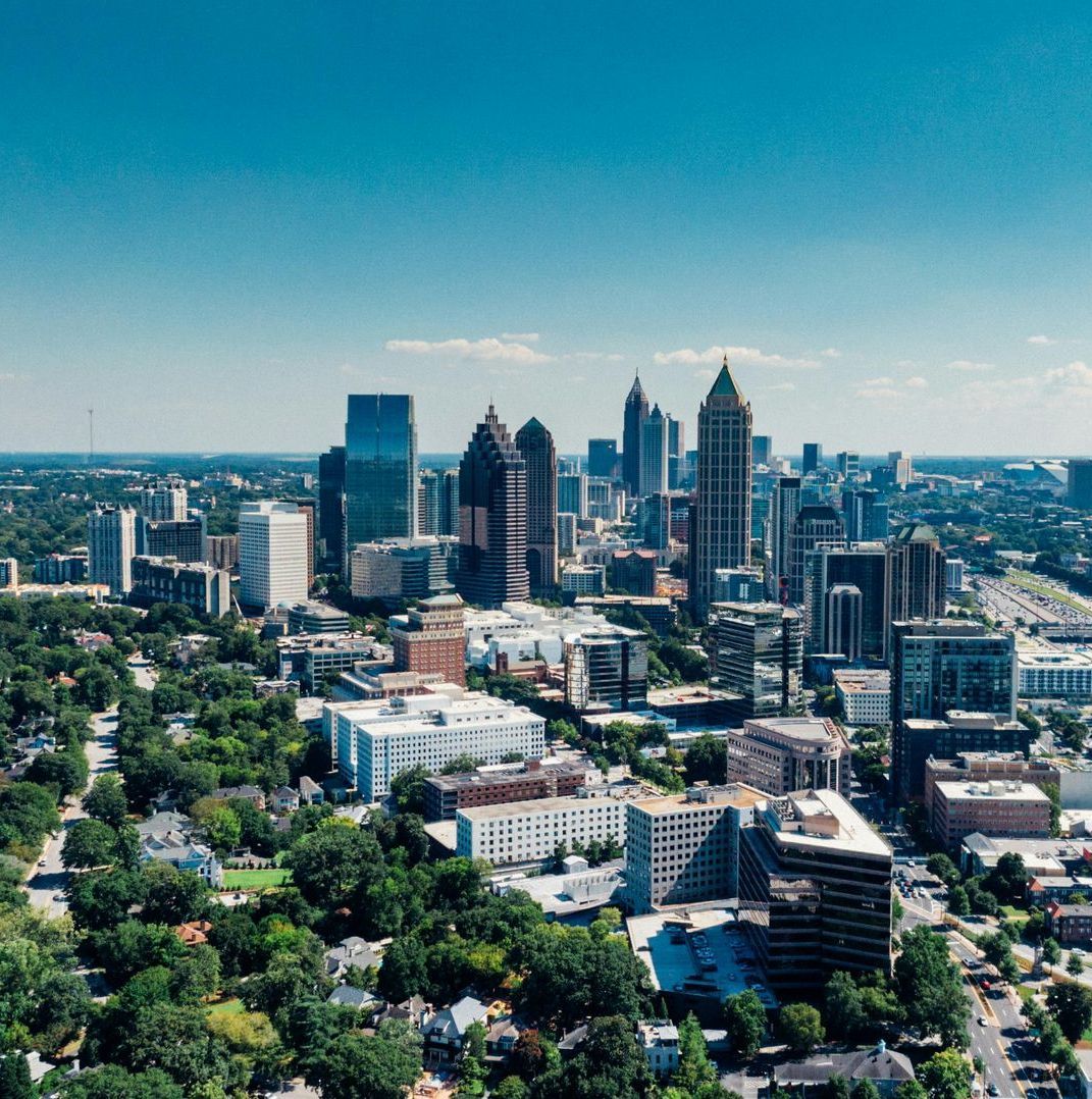 Atlanta, Georgia skyline, with skyscrapers and lush green trees. Sunny day with a clear sky.