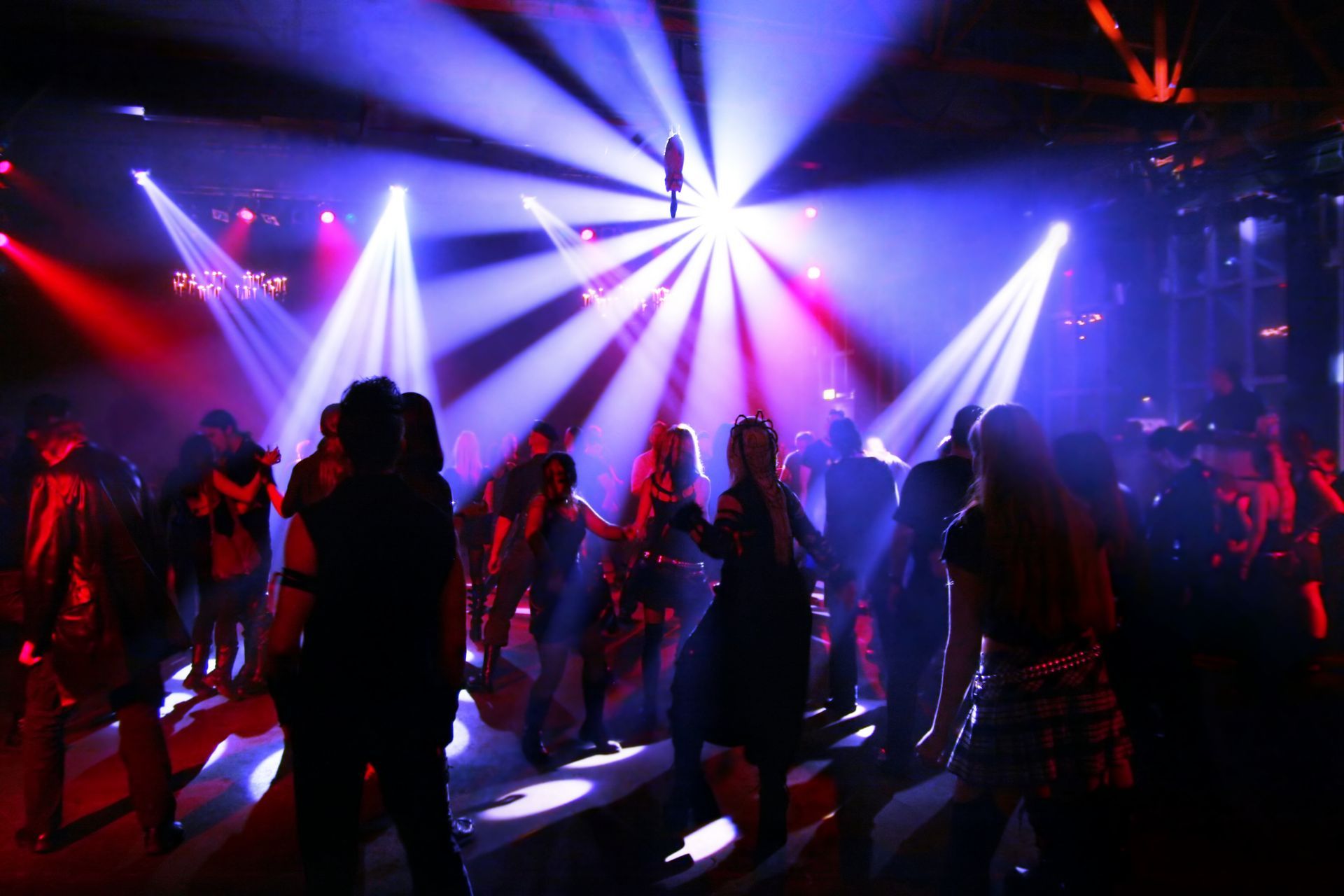 People dancing to music played by DJ Kerry Balearic in a working men's social club under bright red,