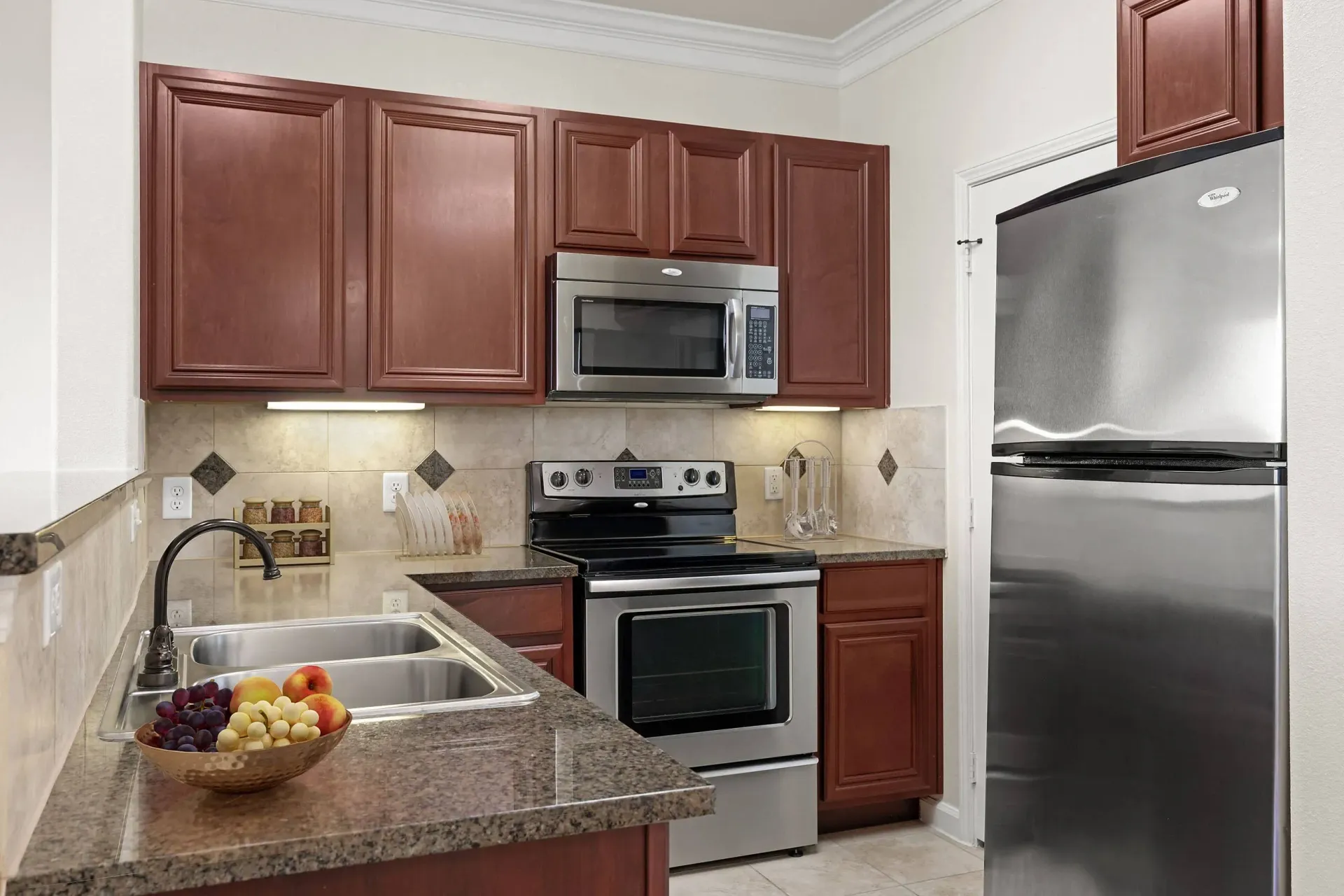 Modern kitchen with stainless steel appliances, granite countertops, and cherry wood cabinets.