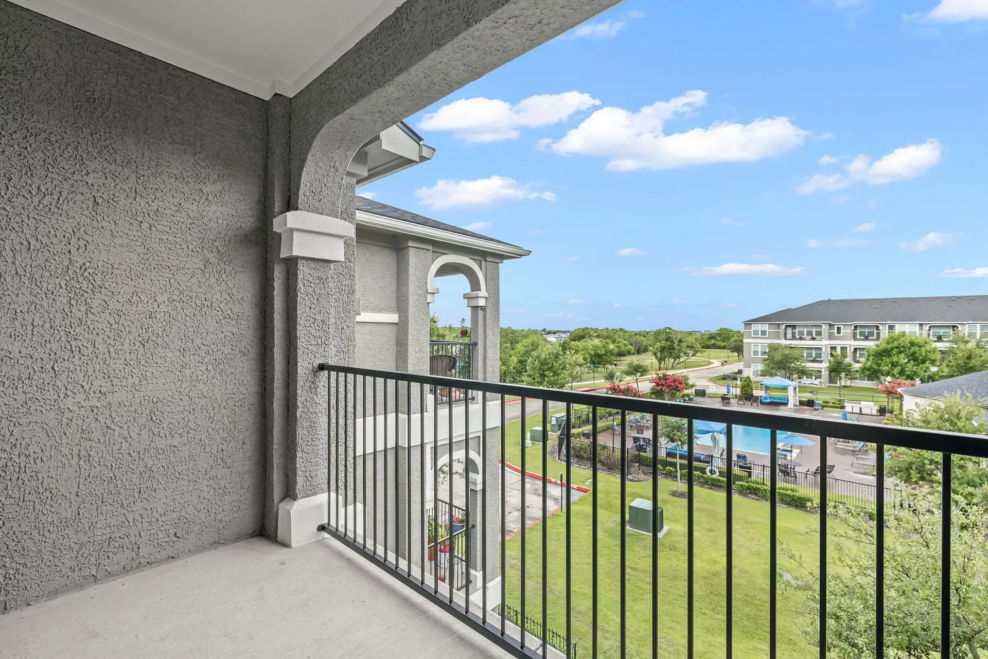 View from balcony overlooking pool and grounds of apartment complex.