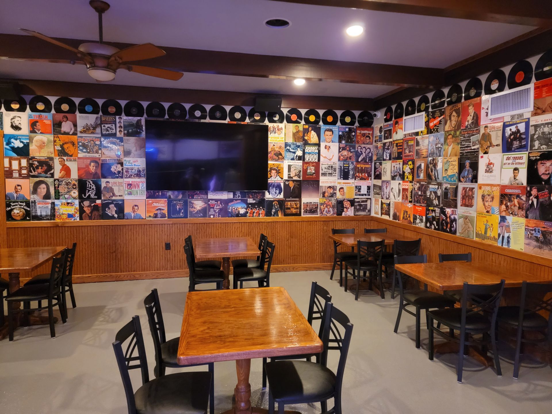 A room with tables and chairs and a large flat screen tv