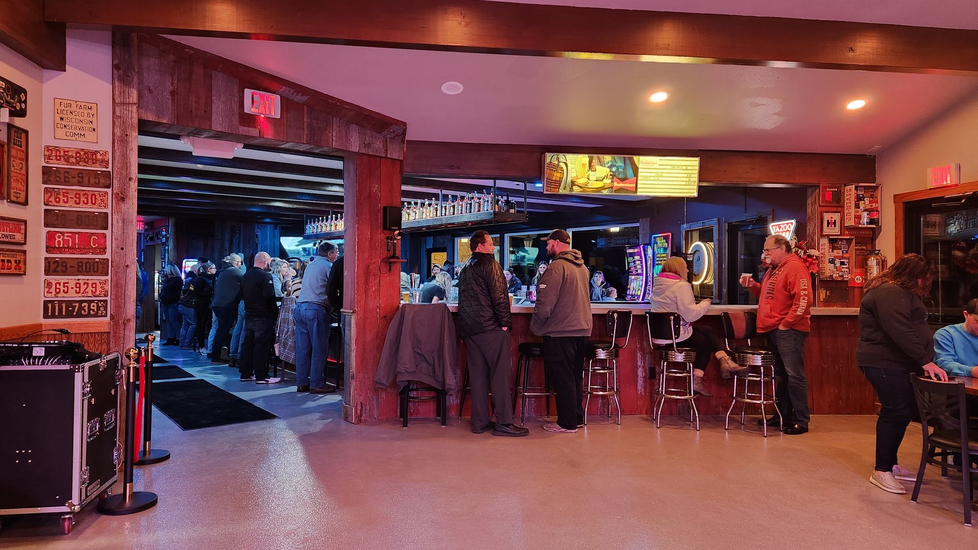 A group of people are standing around a bar in a restaurant.